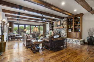 Living room with hardwood / wood-style flooring, a stone fireplace, ceiling fan, and plenty of natural light