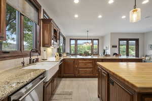 Kitchen featuring dishwasher, butcher block counters, backsplash, and decorative light fixtures