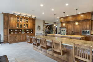 Kitchen featuring a breakfast bar, light stone countertops, hanging light fixtures, and stainless steel appliances