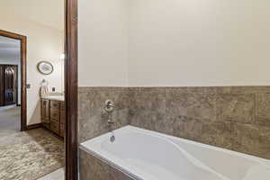 Bathroom featuring vanity, tiled tub, and tile patterned floors