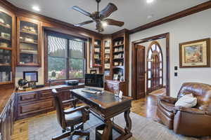 Office space with ornamental molding, light hardwood / wood-style flooring, built in features, and ceiling fan