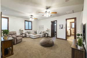 Living room featuring a textured ceiling, light colored carpet, and ceiling fan