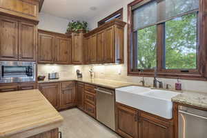 Kitchen featuring tasteful backsplash, stainless steel appliances, sink, light stone counters, and light tile patterned floors