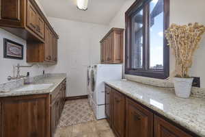 Laundry area with sink, cabinets, light tile patterned floors, independent washer and dryer, and electric panel