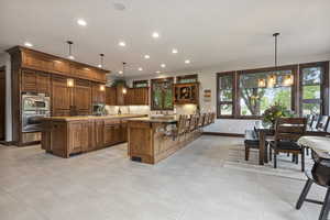 Kitchen featuring double oven, a healthy amount of sunlight, light tile patterned floors, and a kitchen island