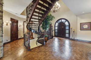 Entrance foyer with parquet flooring, a notable chandelier, and a towering ceiling