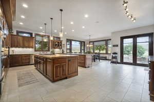 Kitchen with butcher block countertops, french doors, light tile patterned floors, stainless steel dishwasher, and a center island