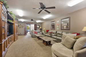 Carpeted living room featuring a textured ceiling and ceiling fan