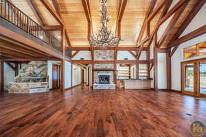 Grand living room featuring a stone fireplace, wooden ceiling, hardwood / wood-style floors, and high vaulted ceiling