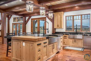 Kitchen featuring light wood-type flooring, dishwasher, a mountain view, beamed ceiling, and a center island with sink