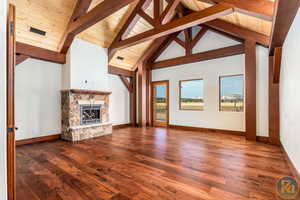 Spacious Primary bedroom featuring  wood flooring, high vaulted ceiling, beamed ceiling, a stone fireplace, and wood ceiling