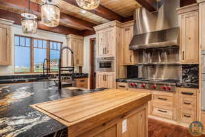 Kitchen with decorative light fixtures, tasteful backsplash, stainless steel appliances, wooden ceiling, and wall chimney exhaust hood