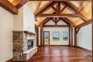 Spacious Primary bedroom featuring wood ceiling, a stone fireplace, beamed ceiling, and wood flooring