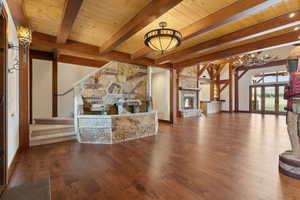 Grand room featuring timber ceiling, a stone fireplace, wood flooring, and tongue and groove ceiling