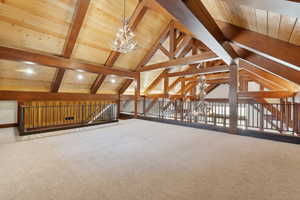 Additional living space with an inviting chandelier, carpet, lofted ceiling with beams, and wood ceiling