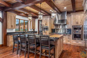 Kitchen featuring dark hardwood / wood-style floors, wood ceiling, a center island with sink, and double oven