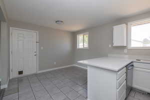 Kitchen with white cabinetry, dishwasher, kitchen peninsula, and light tile patterned floors