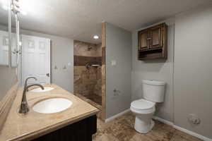 Bathroom with double vanity and shower stall with 2 shower heads. Toilet.