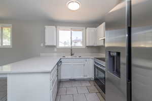 Kitchen with sink, range with electric cooktop, stainless steel refrigerator with ice dispenser, and kitchen peninsula