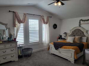 Bedroom featuring carpet floors, multiple windows, ceiling fan, and vaulted ceiling