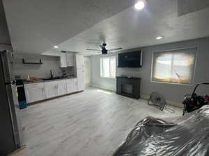 Living room with a textured ceiling, sink, and ceiling fan