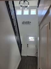 Foyer entrance featuring an inviting chandelier, dark hardwood / wood-style flooring, and a high ceiling