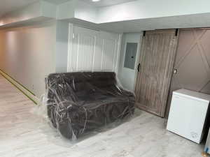 Living area with electric panel and light wood-type flooring