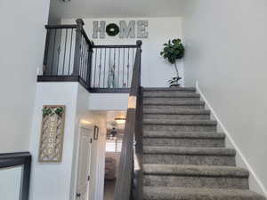 Stairway featuring a high ceiling, ceiling fan, and hardwood / wood-style flooring