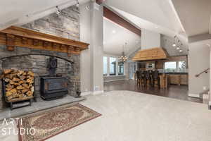 Living room with hardwood / wood-style flooring, a wood stove, high vaulted ceiling, an inviting chandelier, and beam ceiling