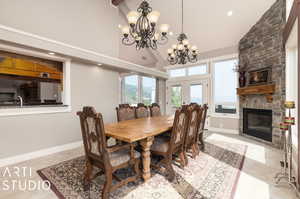 Tiled dining area featuring french doors, an inviting chandelier, a fireplace, sink, and high vaulted ceiling