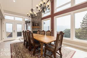 Tiled dining room featuring a notable chandelier, a fireplace, french doors, and a high ceiling