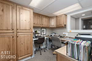 Lower Level Office space featuring light colored carpet, a paneled ceiling, and built in desk