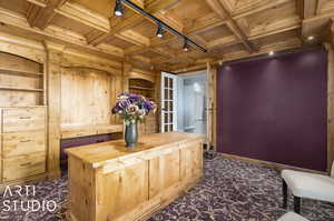 Library space featuring dark carpet, beamed ceiling, and coffered ceiling