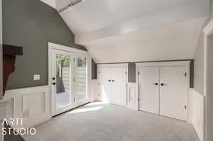 Primary bedroom featuring light carpet and vaulted ceiling