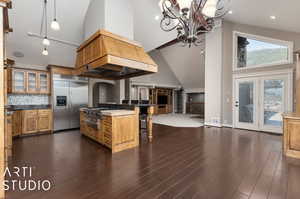 Kitchen featuring a breakfast bar, tasteful backsplash, dark hardwood / wood-style flooring, built in refrigerator, and high vaulted ceiling