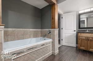 Lower level bathroom featuring tiled tub and vanity