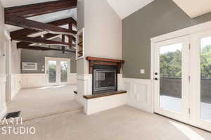 Primary bedroom with high vaulted ceiling, a wall unit AC, beam ceiling, light colored carpet, and french doors