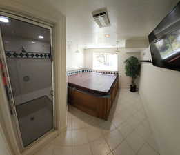 Bathroom featuring a shower with shower door, a textured ceiling, and tile patterned floors