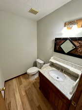 Bathroom featuring vanity, a textured ceiling, hardwood / wood-style flooring, and toilet