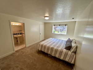 Bedroom featuring ensuite bath, sink, a textured ceiling, and tile patterned floors