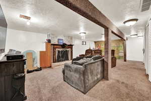 Living room with a fireplace, light carpet, and a textured ceiling