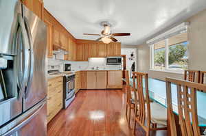 Kitchen with ceiling fan, sink, light hardwood / wood-style floors, appliances with stainless steel finishes, and backsplash