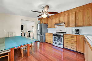 Kitchen with wood-type flooring, ceiling fan, stainless steel fridge with ice dispenser, gas range oven, and backsplash