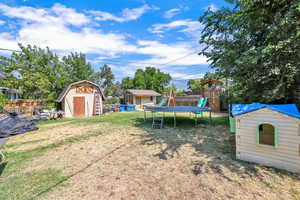 View of yard with a playground, a trampoline, and a storage shed