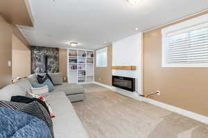 Carpeted living room with a fireplace, built in shelves, a healthy amount of sunlight, and a wood stove