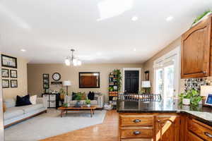 Kitchen with dark stone counters, tasteful backsplash, an inviting chandelier, pendant lighting, and light hardwood / wood-style floors