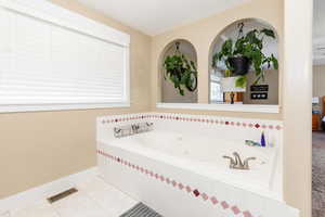 Bathroom with tiled tub and tile patterned flooring