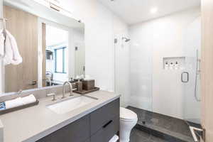 Bathroom featuring a shower with shower door, vanity, tile patterned flooring, and toilet