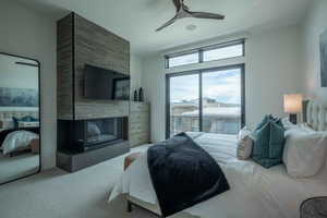 Carpeted bedroom with a multi sided fireplace and ceiling fan