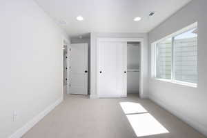 Unfurnished bedroom featuring a closet and light colored carpet